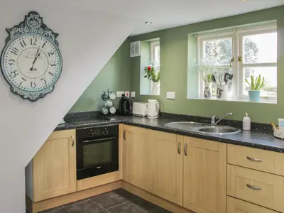 a kitchen with a clock on the wall and a sink at 1 Royal Oak Cottages in Shrewsbury