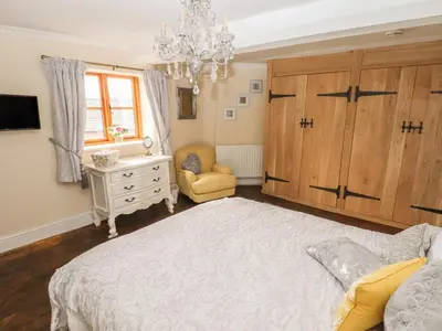 a bedroom with a large bed and a chandelier at Top Farm House in Oswestry