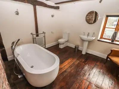 a bathroom with a white tub and a sink at Top Farm House in Oswestry