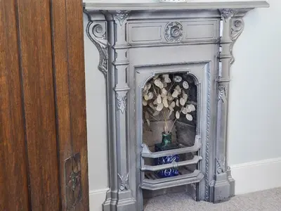 a gray fireplace with a vase of flowers in it at The Mill House, The Square in Talgarth