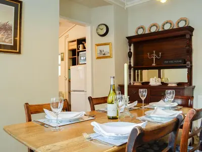 a dining room table with a bottle of wine and glasses at The Mill House, The Square in Talgarth