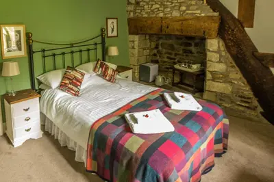 a bedroom with a bed and a stone fireplace at Lower House B&B and Cottages, Adforton in Leintwardine