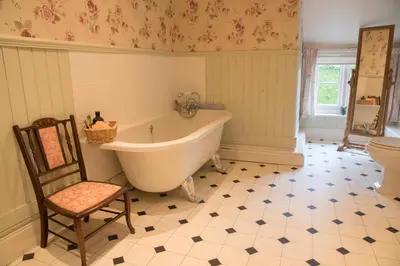a bathroom with a tub and a chair and a toilet at Lower House B&B and Cottages, Adforton in Leintwardine