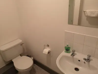 a white bathroom with a toilet and a sink at Ty'r Bont Studios in Newtown
