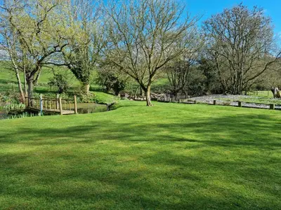 a large green field with trees and a fence at Riverside Cabin - Sleeps 2 - HotTub - Parking in Oswestry