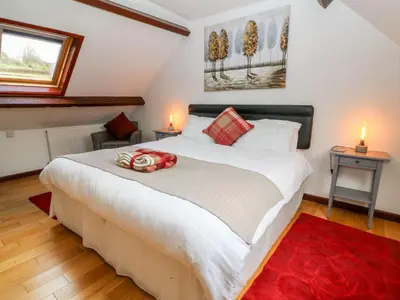 a bedroom with a large white bed with a red blanket at Caecrwn in Brecon