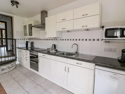 a kitchen with white cabinets and a sink and a microwave at Caecrwn in Brecon