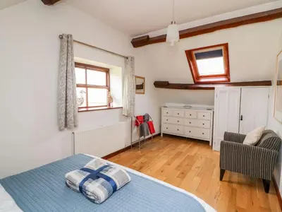 a bedroom with a bed and a chair and window at Caecrwn in Brecon