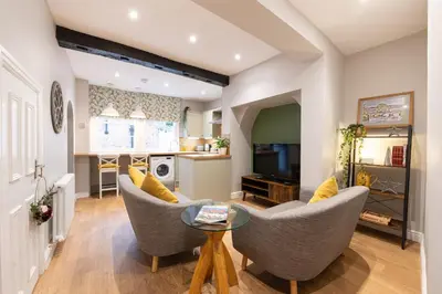 a living room with chairs and a table and a kitchen at Coach House, Shrewsbury Town in Shrewsbury