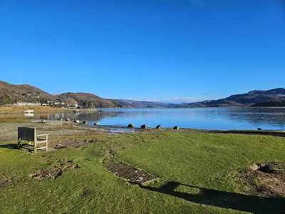 a bench sitting next to a body of water at Ridge And Tides in Fairbourne