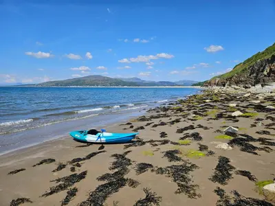 a blue boat sitting on a beach next to the water at Ridge And Tides in Fairbourne