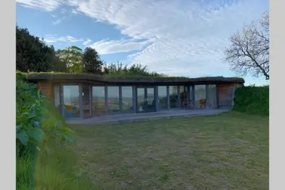 a small house with a grass roof on a field at Wilderness Lodge in Oswestry