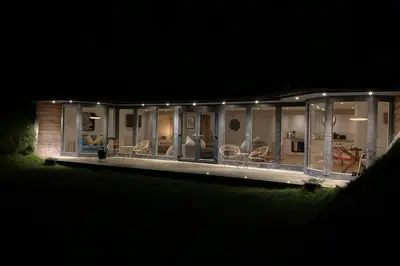 a house lit up at night with chairs at Wilderness Lodge in Oswestry