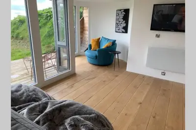 a living room with a blue chair and a sliding glass door at Wilderness Lodge in Oswestry