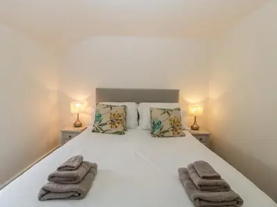 a bedroom with a white bed with towels on it at Bluebell Cottage in Leominster