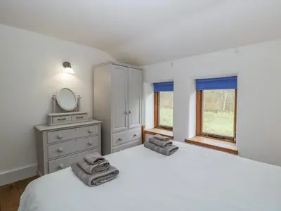 a bedroom with a bed and a dresser and a mirror at Bluebell Cottage in Leominster