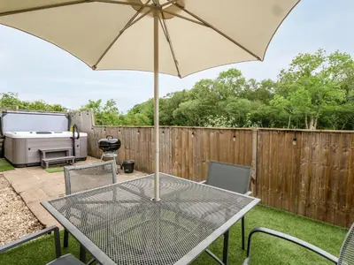 a patio with a table and an umbrella at Beekeeper's Cottage in Leominster