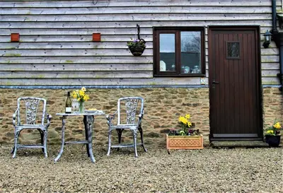 two chairs and a table in front of a building at The Calf Cotts in Pembridge