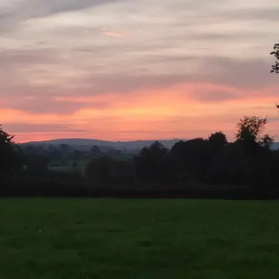 a sunset over a field with a green field at The Calf Cotts in Pembridge