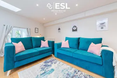 a living room with blue couches and pink pillows at High Quality 2 Bedroom Church Apartment 5 Mins to Town Centre - Free Parking in Shrewsbury