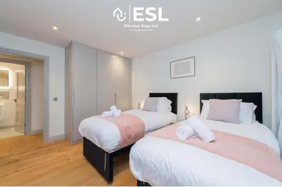 two beds in a bedroom with white walls and wood floors at High Quality 2 Bedroom Church Apartment 5 Mins to Town Centre - Free Parking in Shrewsbury