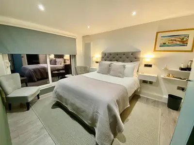 a bedroom with a large bed and a living room at Tŷ Treflan in Aberdyfi