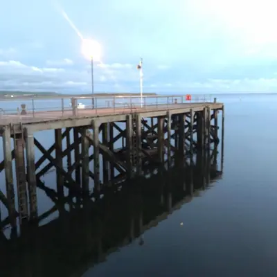 a pier with a light on top of the water at Tŷ Treflan in Aberdyfi
