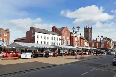 a city street with buildings and a market with umbrellas at Cosy, elegant apartment in heart of Ludlow Town in Ludlow