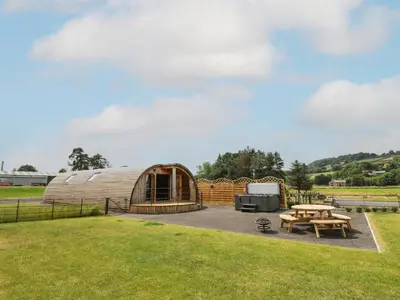 a wooden yurt with a picnic table and a grill at Bluebell in Rhayader