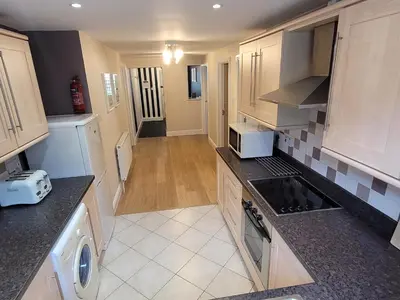 a kitchen with white cabinets and black counter tops at Llys Bach Apartment at Llys Aeron in Aberaeron