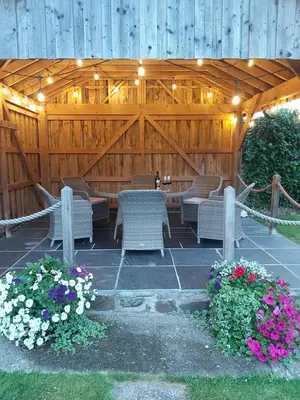 a patio with chairs and flowers in front of a wooden fence at Llys Bach Apartment at Llys Aeron in Aberaeron