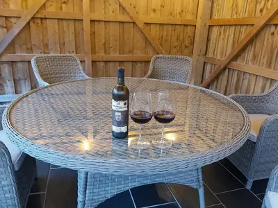 a table with wine glasses and a bottle of wine at Llys Bach Apartment at Llys Aeron in Aberaeron