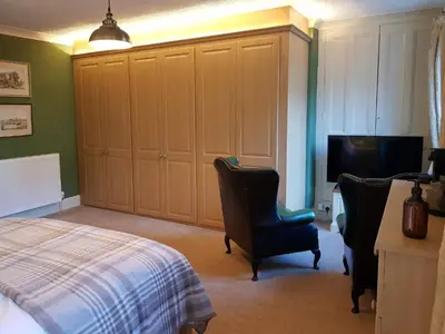 a bedroom with a bed and two chairs and a television at Afallon Townhouse in Dolgellau