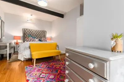 a bedroom with a yellow chair and a dresser at No 31 Promenade APARTMENT by the sea in Aberystwyth