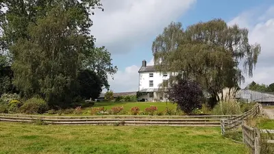 a white house with a fence in a field at Upper Buckton B&B in Leintwardine