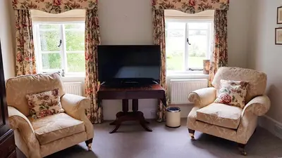 a living room with two chairs and a flat screen tv at Upper Buckton B&B in Leintwardine