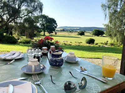 a table with plates and utensils on a table with a view at Upper Buckton B&B in Leintwardine