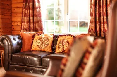 a leather couch with pillows in a room with a window at Stunning Log Cabin with Garden in Snowdonia - Hosted by Seren Short Stays in Trawsfynydd