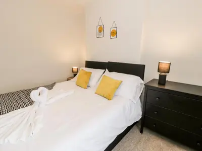 a bedroom with a white bed with two yellow pillows at Rose Suite in Barmouth