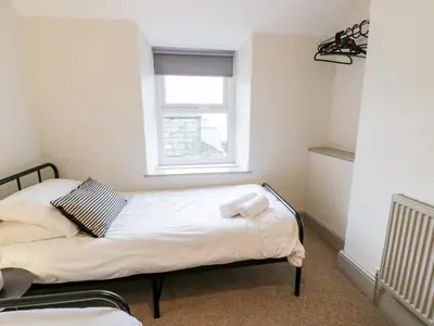two beds in a small room with a window at Rose Suite in Barmouth