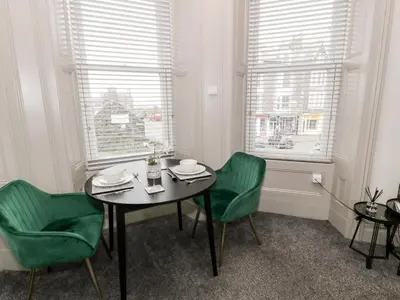 a dining room with a table and two green chairs at Emerald Suite in Barmouth