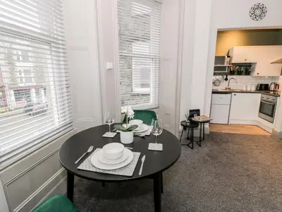 a dining room with a table and a kitchen at Emerald Suite in Barmouth