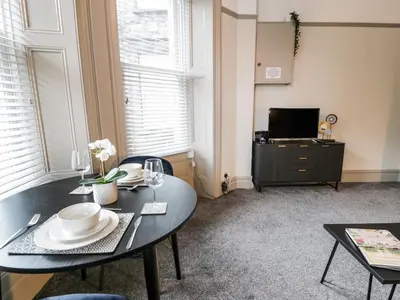 a living room with a table and a tv at Sapphire Suite in Barmouth