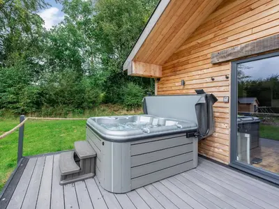 a hot tub sitting on a deck next to a building at Dwrgi - Uk32923 in Cwrt-newydd