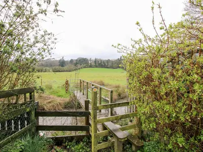 a wooden staircase leading into a field with a fence at The Wheelhouse at Dudgeley Mill in Church Stretton