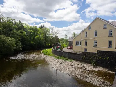 a river with a building next to a house at Riverbank Bed and Breakfast in Llanwrtyd Wells