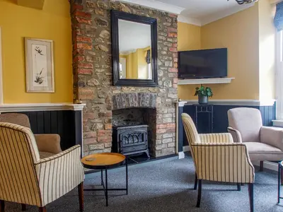 a living room with a fireplace with chairs and a mirror at Riverbank Bed and Breakfast in Llanwrtyd Wells