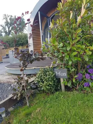 a sign in the grass in front of a house at Great House Farm Luxury Pods and Self Catering in Crickadarn
