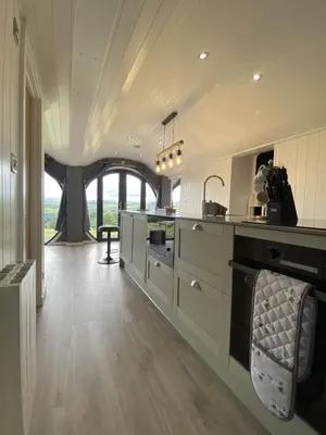 a large kitchen with white cabinets and a large window at Great House Farm Luxury Pods and Self Catering in Crickadarn