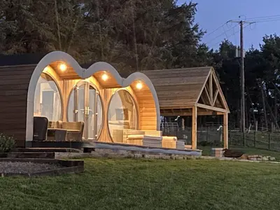 a tiny house with a curved roof and windows at Great House Farm Luxury Pods and Self Catering in Crickadarn